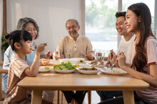 Asian Big Happy Family Eat Foods On Dinner Table Together In House.
