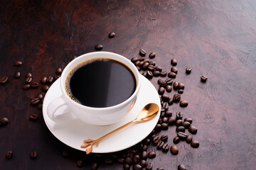 White coffee cup with dark black coffee on a saucer and spoon. and freshly roasted aromatic coffee beans in sacks on a dark background. top view.