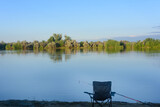 Fototapeta Pomosty - Morning fishing on river. Fisherman's chair and fishing rod with bell. Selective focus, blur