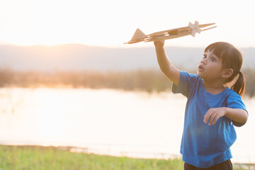 dreams of flight! child playing with toy airplane against the sky at sunset