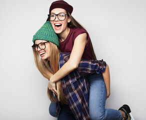 Two young beautiful smiling hipster girls in trendy summer clothes.