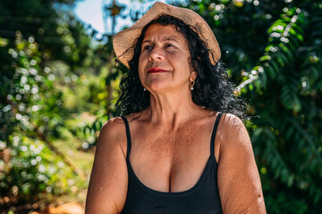 Wall Mural - Portrait of a beautiful Latin female farmer. Brazilian woman at farm in summer day. Gardening activity. Brazilian elderly woman. Latin people.