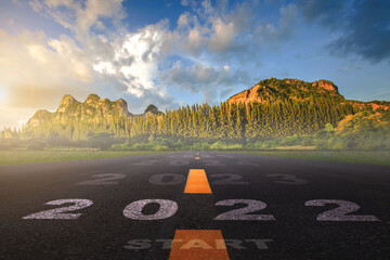 2022, The New Year 2022 or the beginning of the concept of the word 2022 is written on the road in the middle of the asphalt road with a sunset mountain backdrop, concepts of planning and challenges