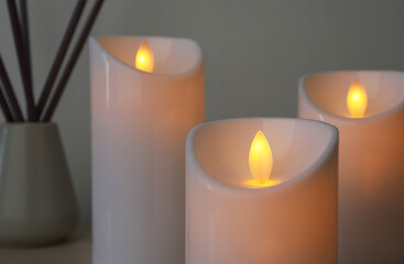 Wall Mural - Glowing decorative LED candles on grey background, closeup view