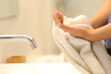 Woman drying hands with a towel in the bathroom