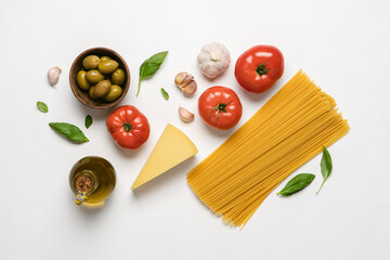 Wall Mural - Italian cuisine white background. Red tomatoes, spaghetti, olives, basil, olive oil, garlic top view. Ingredients for cooking pasta with tomato sauce. Mediterranean  food background