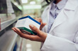 © StratfordProductions - Closeup of hands of young woman holding medicine box reading name in chemist