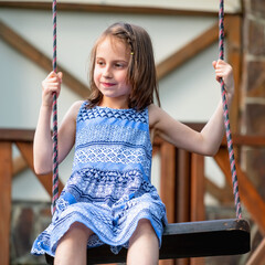 Portrait of beautiful young girl having fun on a swing. Summer, vacation, leisure and happy childhood concept.