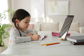 Canvas Print - Little girl doing homework with modern tablet at home