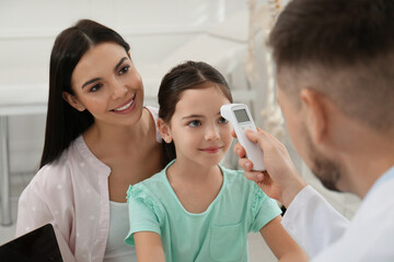 Poster - Mother with daughter visiting pediatrician in hospital. Doctor measuring little girl's temperature