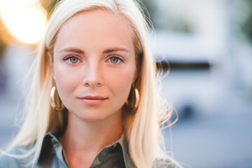 Wall Mural - Beautiful blonde young girl 20-24 year old posing over city background close up. Looking at camera. Attractive woman with blue eyes.