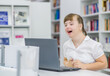 laughing yung girl with syndrome down uses a laptop at library. Education for disabled children concept