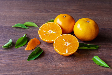 Fresh orange fruit and orange fruit cut in half on a wooden table