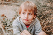 © Svetlana Glazkova - Portrait cute cool blonde caucasian Happy smiling little young boy in casual grey hoodie sitting in the tall grass against the backdrop of nature.