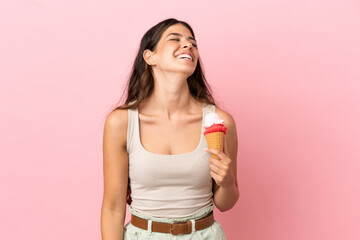 Wall Mural - Young caucasian woman with a cornet ice cream isolated on pink background laughing