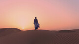Fototapeta  - Portrait of beautiful Arab woman weared in blue traditional dress in the desert during sunset.