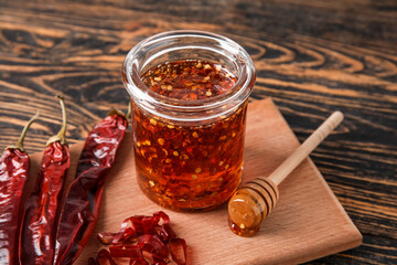 Wall Mural - Jar of hot honey and dry chili peppers on wooden background