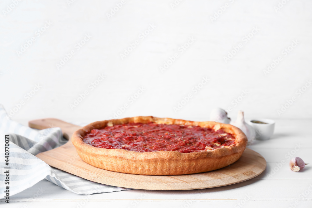 Board with tasty Chicago-style pizza on light background