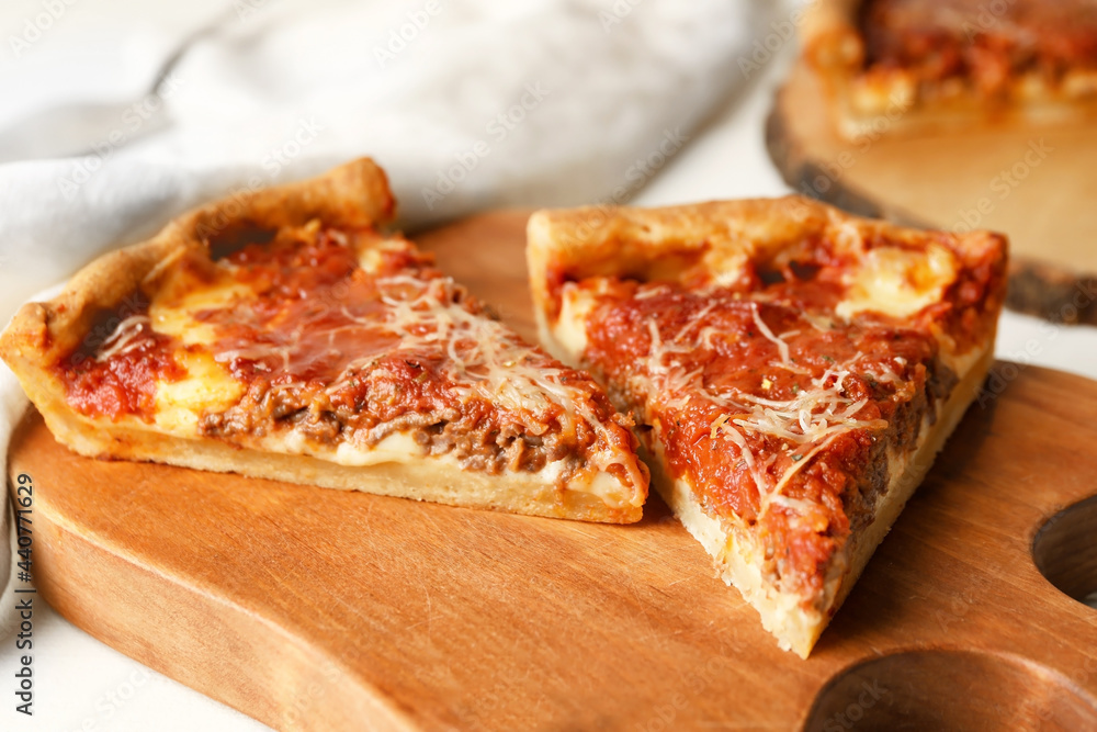Board with tasty Chicago-style pizza on light background, closeup