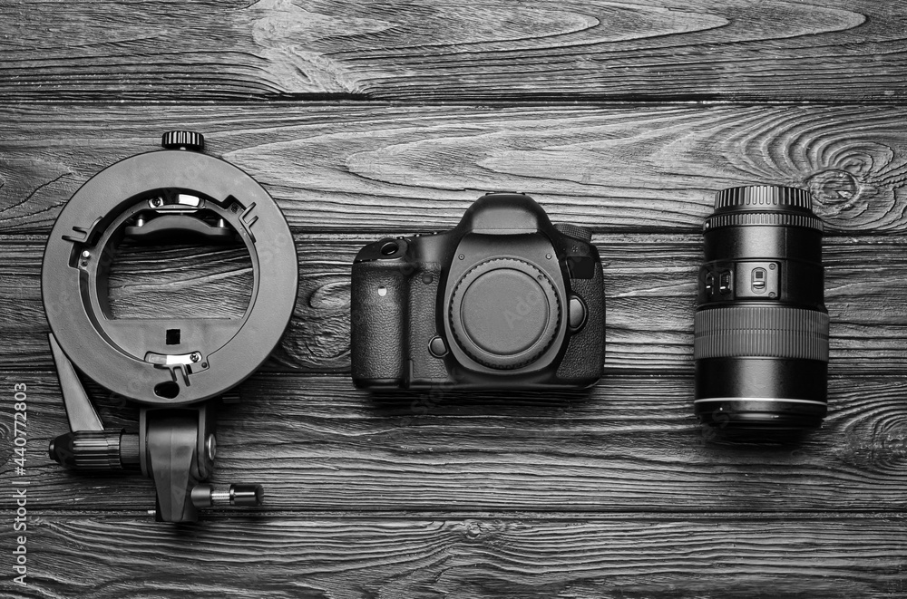 Digital camera, lens and ring flash on dark wooden background