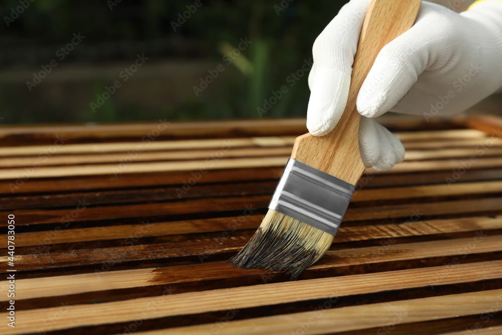 Worker applying wood stain onto planks outdoors, closeup - obrazy, fototapety, plakaty 