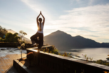 Sticker - Woman doing yoga at dawn near a volcano on the island of Bali