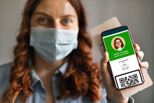 Traveler Woman Wearing A Face Mask Holding A Passport, Ticket Pass And Smartphone With Digital Health Passport App. Covid-19 Health Passport.