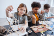 © Seventyfour - Diverse group of children making wooden models during art and craft class in school, copy space