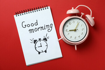 Notebook with Good morning and alarm clock on red background