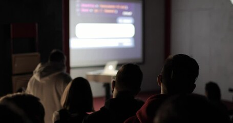 Wall Mural - A group of young people listening to a lecture seminar of a teacher-trainer using a projection screen and laptop. Education concept.