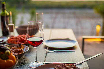 A glass of wine with grilled meat on the summer terrace.A glass of wine at sunset with dinner in the summer.Picnic.Dinner on the street with wine.Meat on a skewer with salad.Mediterranean diet.Summer 