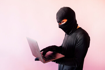 thief man dressed in black with laptop