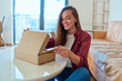 © Goffkein - Young happy joyful smiling girl customer received parcel and unpacking cardboard box with online store order, good shipping delivery service