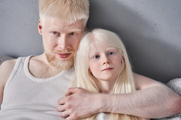 Wall Mural - Man embracing his lovely blonde daughter while laying together at the bed