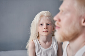 Wall Mural - Girl sitting near her father and looking attentively to the camera while posing