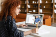 © Vadim Pastuh - E-studying concept. Curly female student watching online educational webinar, listening a senior male teacher with whiteboard on the screen, preparing to exams online, takes notes