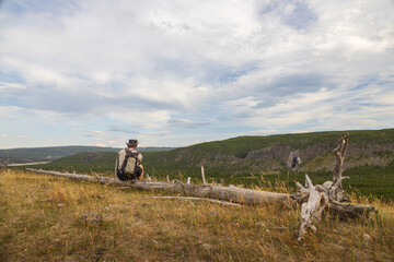 Hiker sitting on log with Fairy Falls in background at Yellowstone National Park