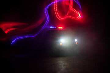 Wall Mural - Police car chasing a car at night with fog background. 911 Emergency response police car speeding to scene of crime. Selective focus