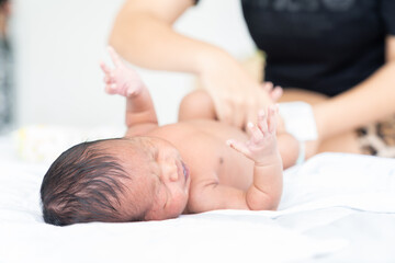 Wall Mural - Mom wiping her newborn baby skin, face with wet wipes carefully on bed at home. family, cleaning wipe and infant concept