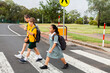 © Austockphoto - Three public school kids walking to school - crossing the road at a pedestrian crossing