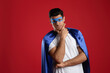 Man wearing superhero cape and mask on red background. Space for text