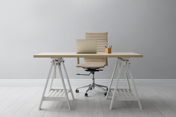 Sticker - Stylish workplace with laptop and comfortable armchair near light wall indoors. Interior design