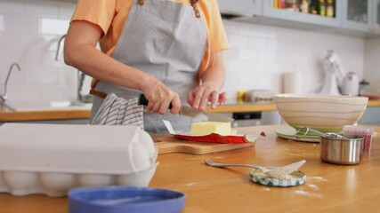 Wall Mural - culinary, baking and cooking food concept - young woman cutting butter with knife on kitchen at home