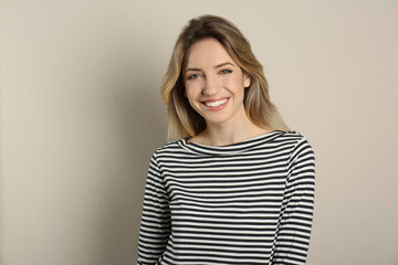 Wall Mural - Portrait of happy young woman with beautiful blonde hair and charming smile on beige background