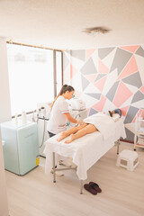 Poster - Vertical shot of female physical therapist doing ultrasonic cavitation therapy on a woman in spa