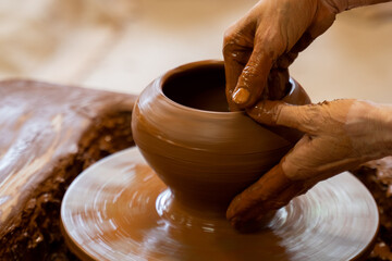 Wall Mural - Elderly hands of a potter, creating an earthen jar on the circle. Old woman makes hand made ceramics from clay