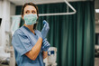 © Rawpixel.com - Female nurse with a mask putting on gloves