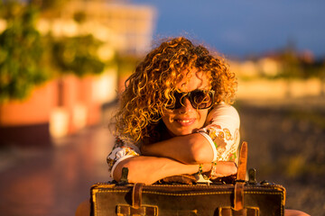 Sticker - Sunset time portrait colors of beautiful adult young woman have relax in leisure activity alone - smile and travel concept with old fashion vintage luggage