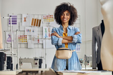 African-American entrepreneur with crossed hands poses for camera in sewing workshop