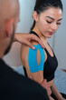 © ADDICTIVE STOCK - Physical therapist applying kinesiology tapes on shoulder of sportswoman